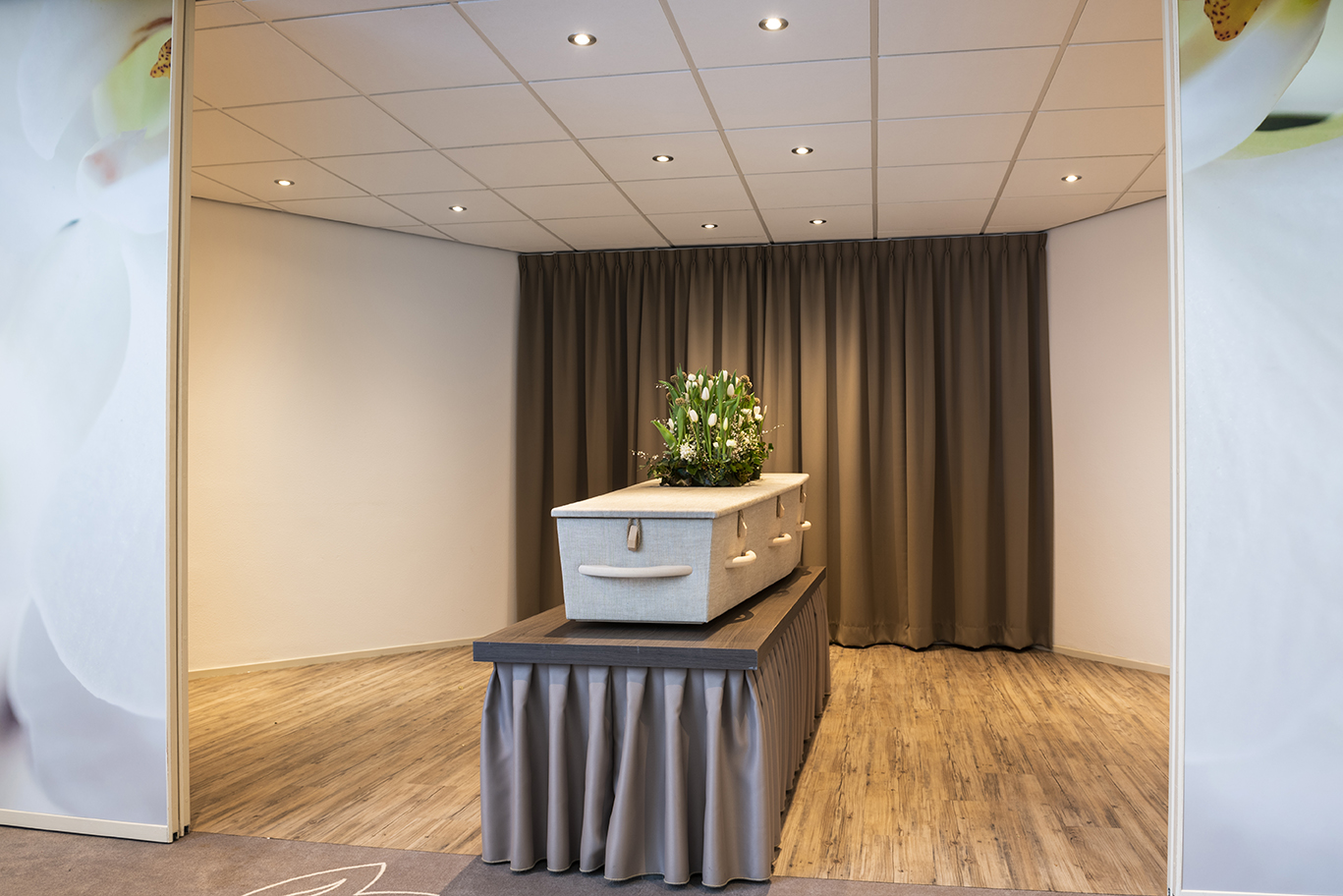 Uitvaartkist met rouwbloemstuk in de opbaarruimte in rouwcentrum Overschie